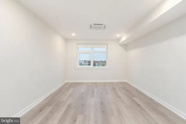 an empty room with wooden floor windows and ceiling fan