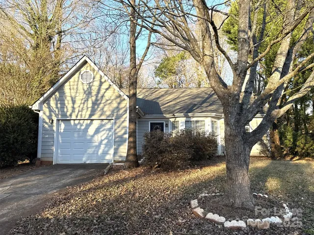 an empty room with wooden floor fireplace and chandelier