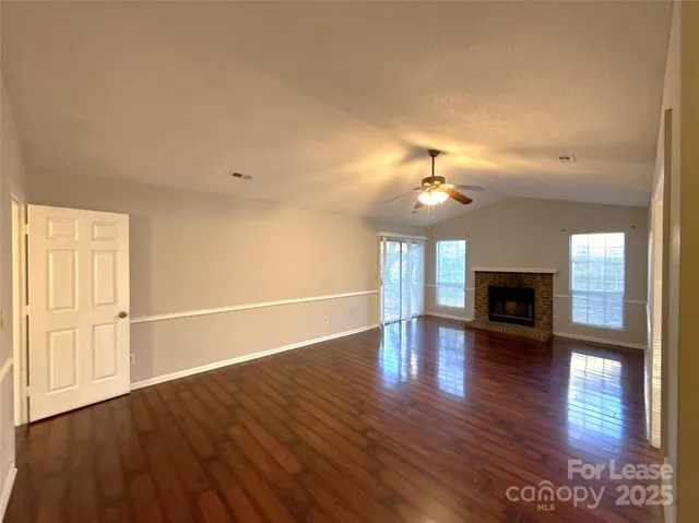 an empty room with wooden floor fireplace and chandelier
