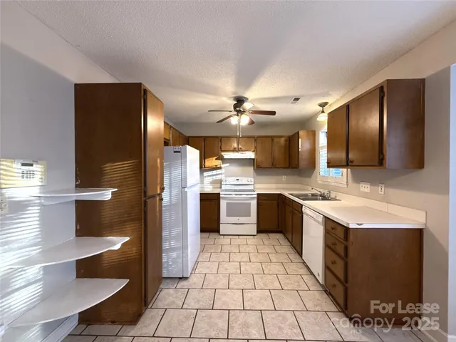a large kitchen with a large counter top a sink stainless steel appliances and cabinets