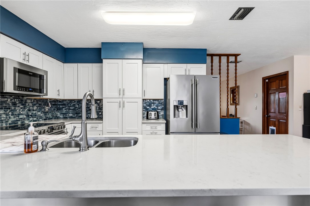 831 Clearmont Street Sebastian, FL 32958 - Photo 11 of 24 a kitchen with stainless steel appliances a refrigerator a stove a microwave a sink and white cabinets