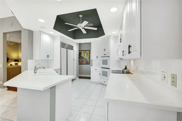 a large white kitchen with a white table chairs and a refrigerator