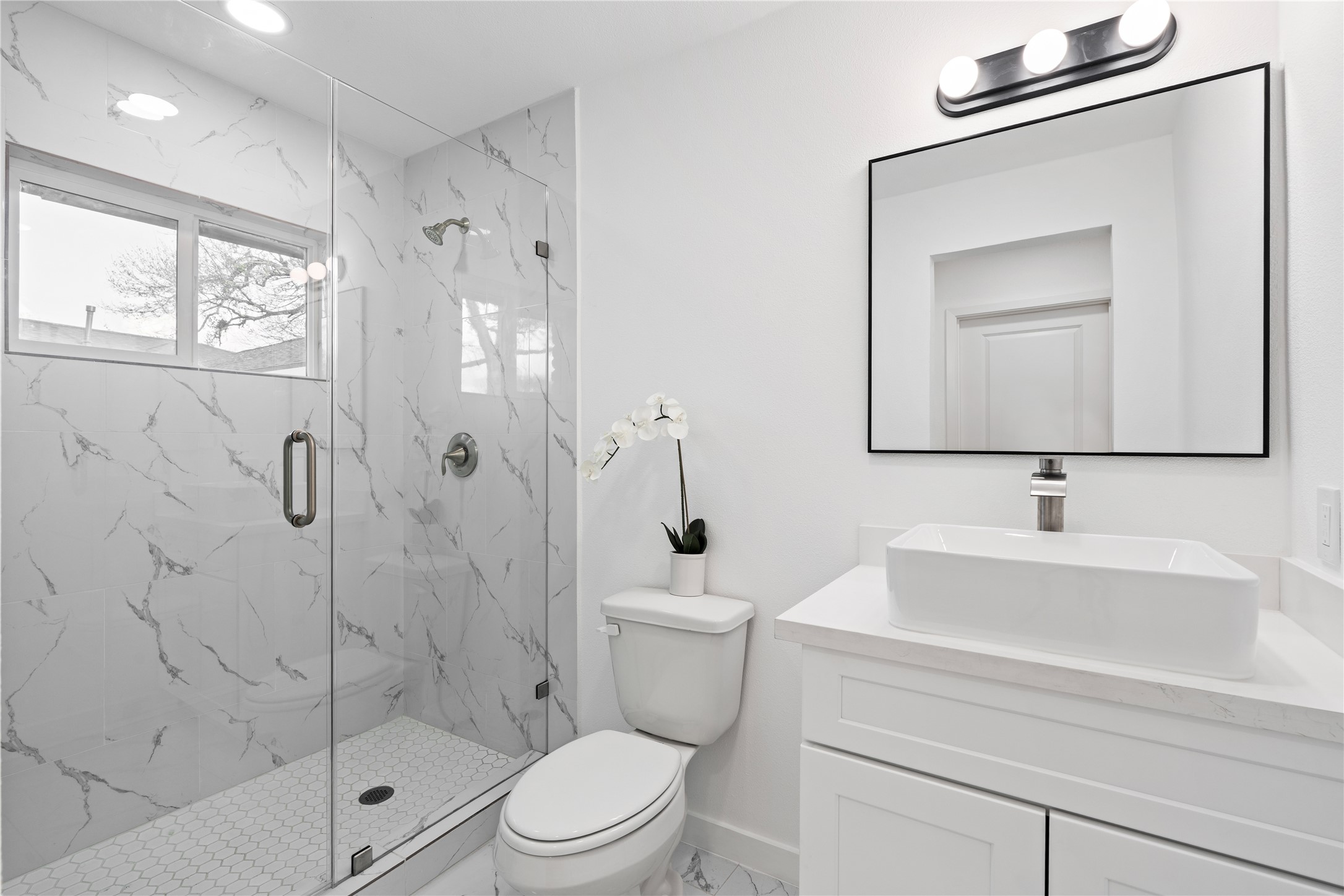 5023 Redstart Street Houston, TX 77035 - Photo 26 of 34 Indulge in luxury with this stunning ensuite bath, featuring a massive glass-enclosed shower with custom marble-style tile and a modern vessel sink.