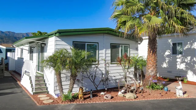 a front view of multi story residential apartment building with sign board and palm trees