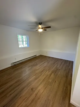 an empty room with wooden floor chandelier fan and windows