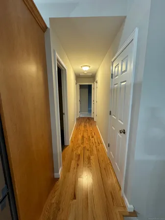 a view of a hallway with wooden floor and a bathroom