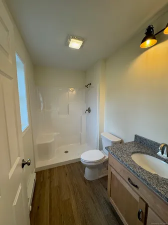 a bathroom with a granite countertop sink toilet a mirror a bathtub and shower