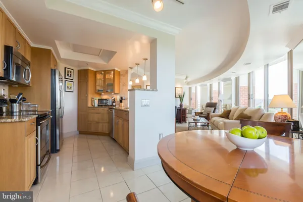 a living room with stainless steel appliances furniture a rug and a kitchen view