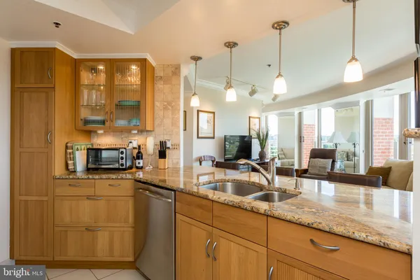 a view of a kitchen with a sink a counter top space and living room view