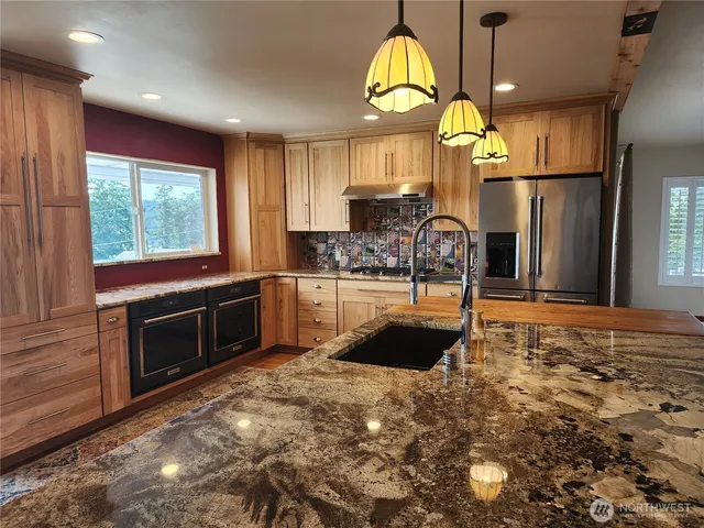 a kitchen with kitchen island granite countertop a stove a sink and a refrigerator