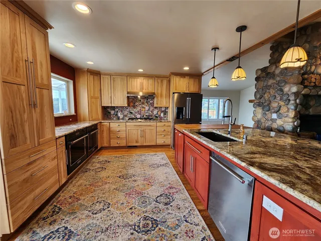 a large kitchen with stainless steel appliances granite countertop a stove a sink and a refrigerator