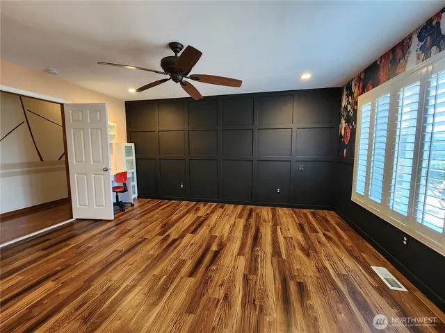 a view of empty room with wooden floor and fan