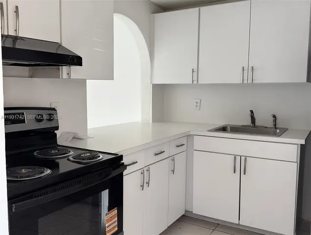 a kitchen with white cabinets and black appliances