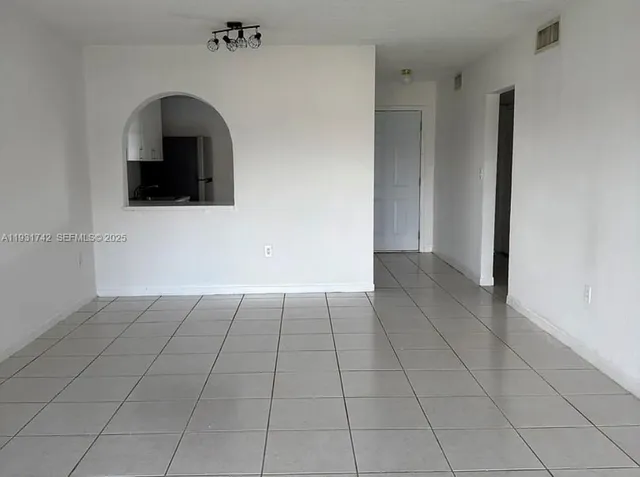 a view of an empty room with cabinet and a window