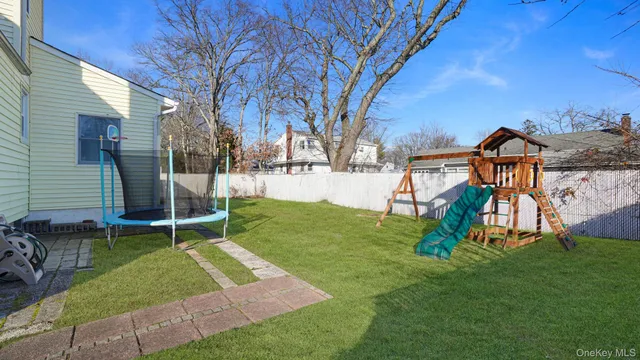 a backyard of a house with wooden fence and large trees