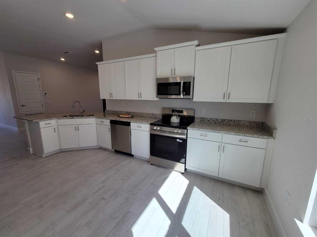 4465 Southwest 91st Ln Road Ocala, FL 34476 - Photo 6 of 42 a kitchen with granite countertop white cabinets and white appliances