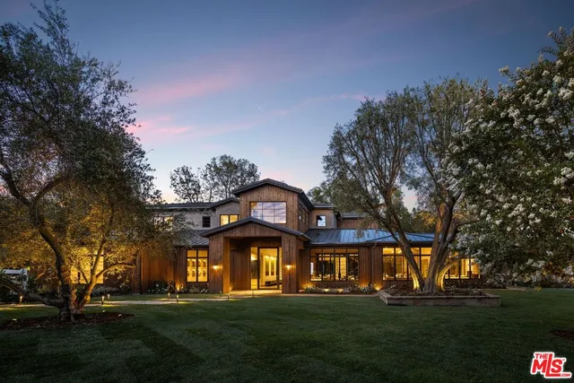 a view of a white house with a big yard and large trees