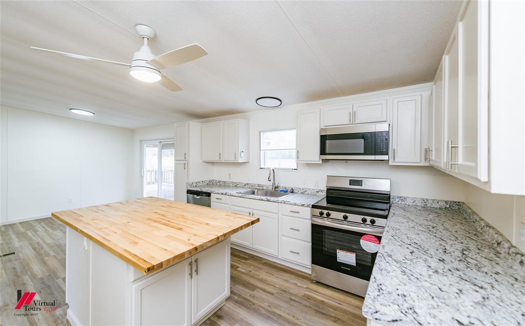 Kitchen featuring appliances with stainless steel finishes, white cabinetry, wooden counters, and light wood-style floors