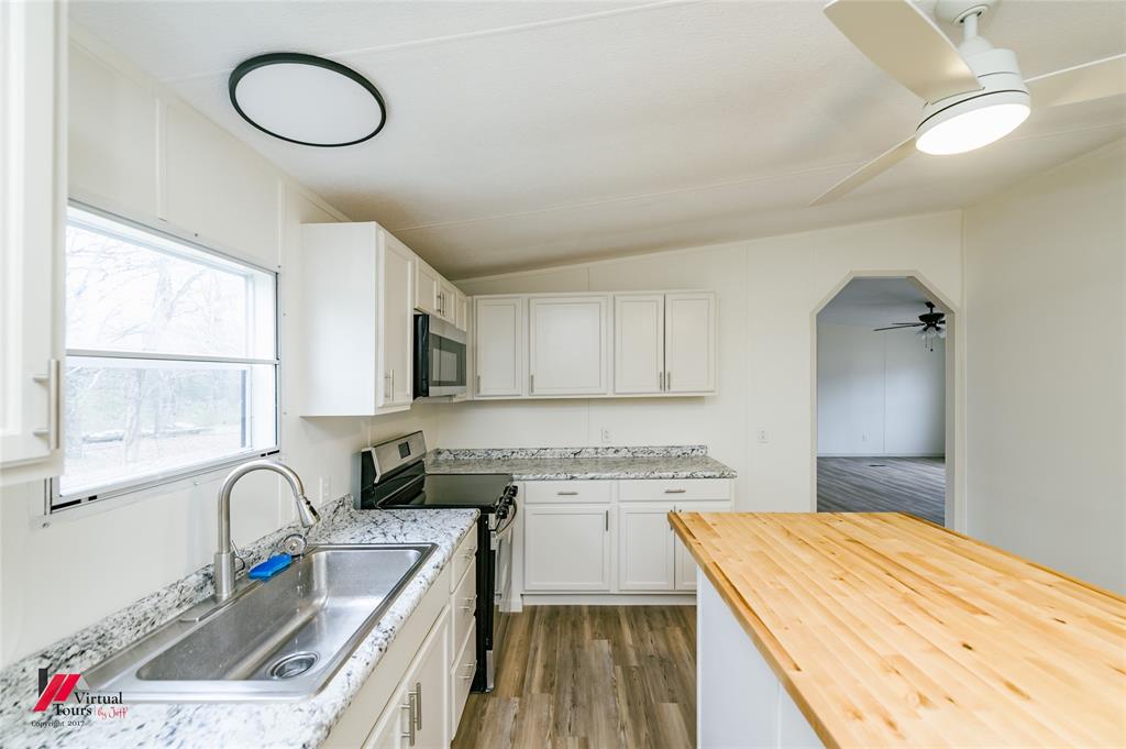 4947 Quiet Acres Road Shreveport, LA 71107 - Photo 3 of 39 Kitchen with butcher block counters, stainless steel appliances, white cabinets, vaulted ceiling, and light wood-style flooring