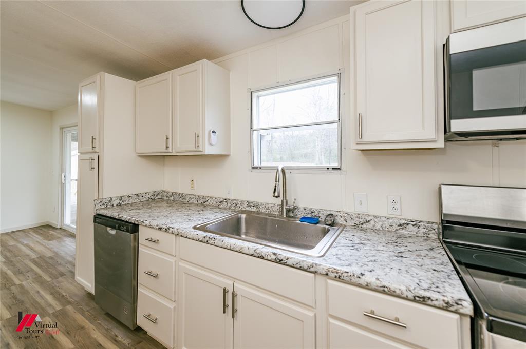 4947 Quiet Acres Road Shreveport, LA 71107 - Photo 33 of 39 Kitchen with stainless steel appliances, light countertops, dark wood-style flooring, and white cabinetry