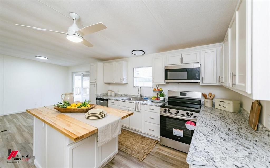 4947 Quiet Acres Road Shreveport, LA 71107 - Photo 4 of 39 Virtually Staged Kitchen with butcher block countertops, appliances with stainless steel finishes, light wood-type flooring, white cabinetry, and a center island