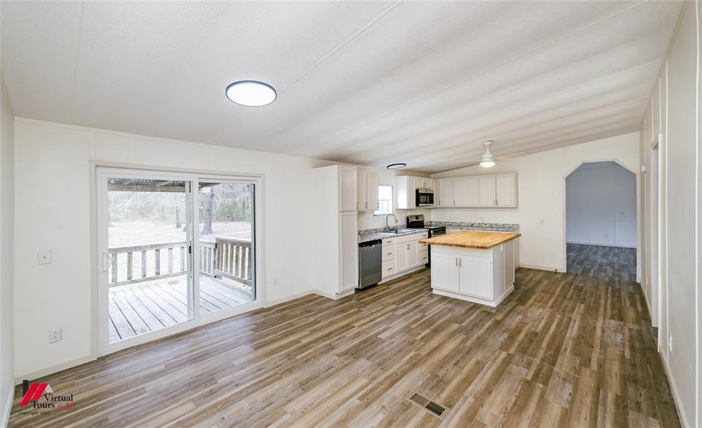 4947 Quiet Acres Road Shreveport, LA 71107 - Photo 6 of 39 Kitchen featuring white cabinets, arched walkways, a kitchen island with a butcher block countertop, and light wood-style floors