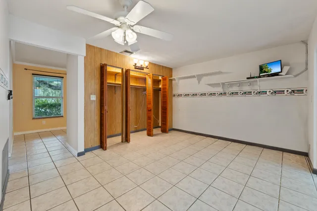 a view of an empty room with wooden floor and a ceiling fan