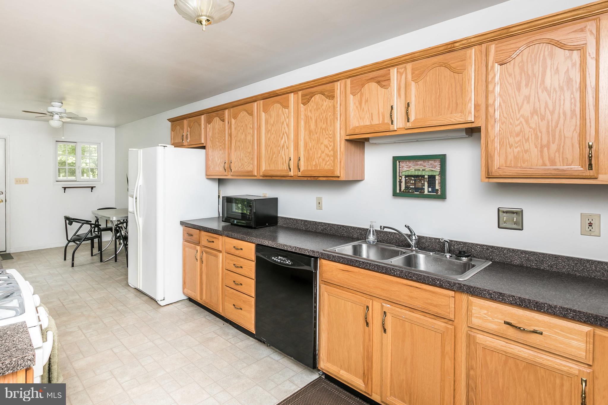 2414 Steele Road Baltimore, MD 21209 - Photo 14 of 24 a kitchen with granite countertop wooden cabinets a sink a stove a window and stainless steel appliances