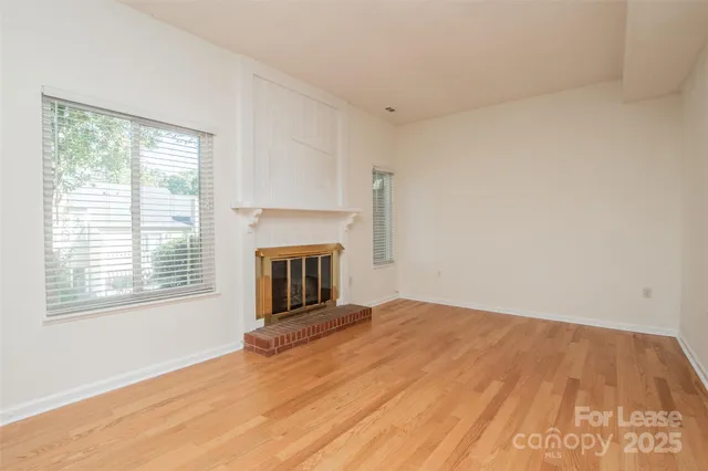 a view of empty room with wooden floor and fireplace