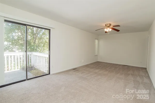 an empty room with chandelier fan and windows