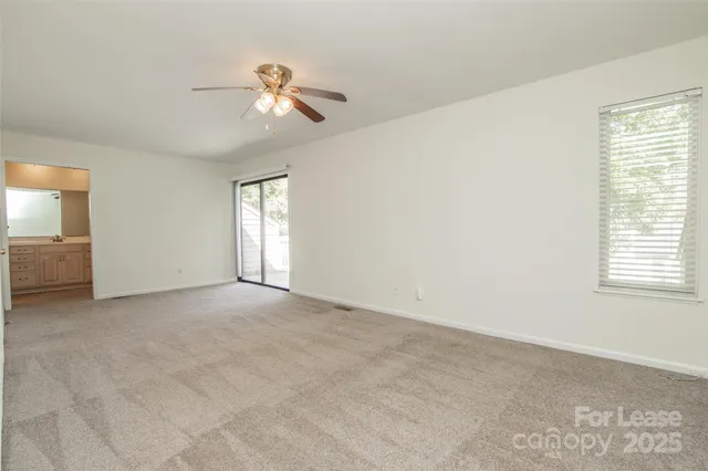 an empty room with windows and fan
