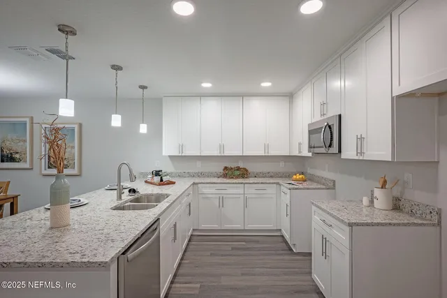 a kitchen with a sink dishwasher and white cabinets with wooden floor