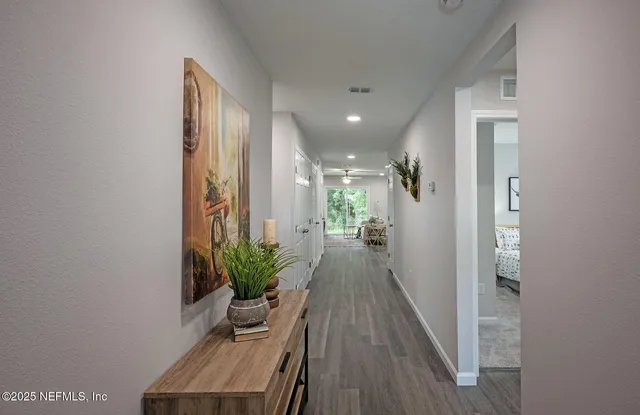 a view of a hallway with wooden floor and a potted plant