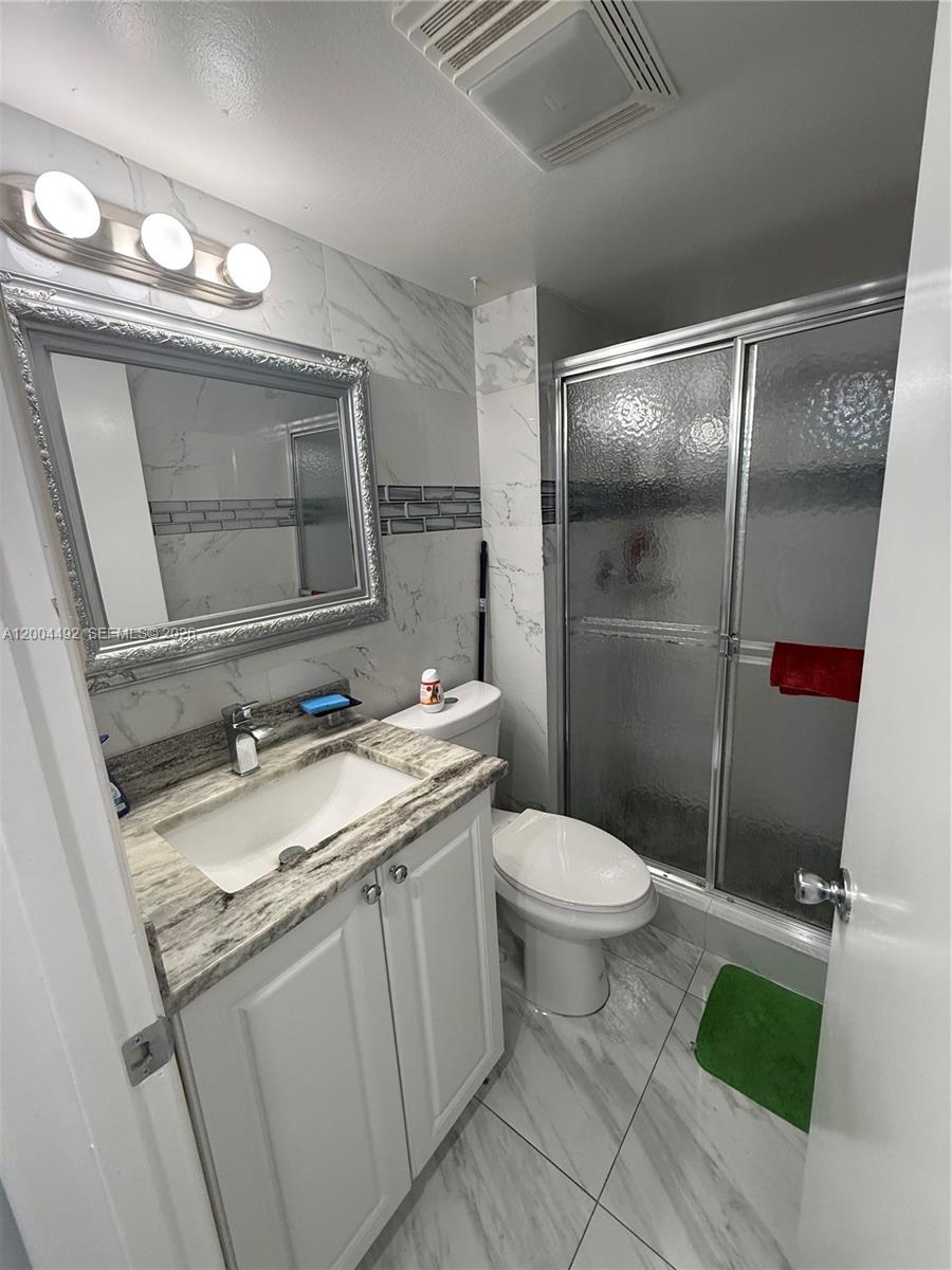 9880 Marina Boulevard, Unit 1528 Boca Raton, FL 33428 - Photo 12 of 14 a bathroom with a granite countertop toilet sink and mirror