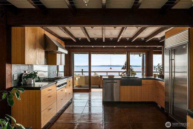 a kitchen with stainless steel appliances kitchen island granite countertop a stove a sink and dishwasher with wooden floor