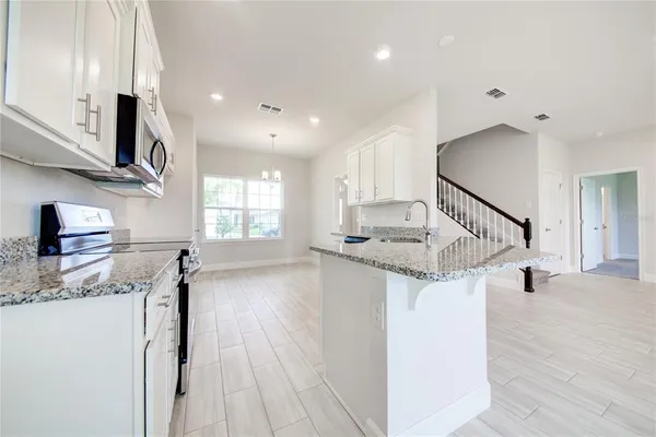 a kitchen with stainless steel appliances granite countertop a stove a sink and a microwave