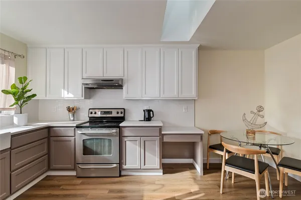 a kitchen with a stove a sink and white cabinets