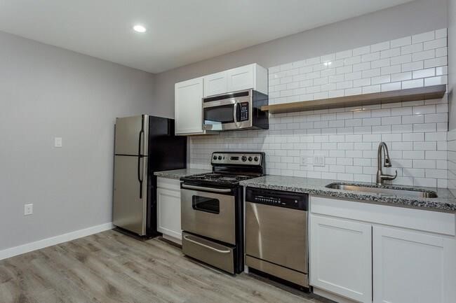 2810 Beauchamp Street, Unit 28 Houston, TX 77009 - Photo 2 of 12 a kitchen with stainless steel appliances granite countertop white cabinets a refrigerator a stove a microwave oven and a sink with wooden floor