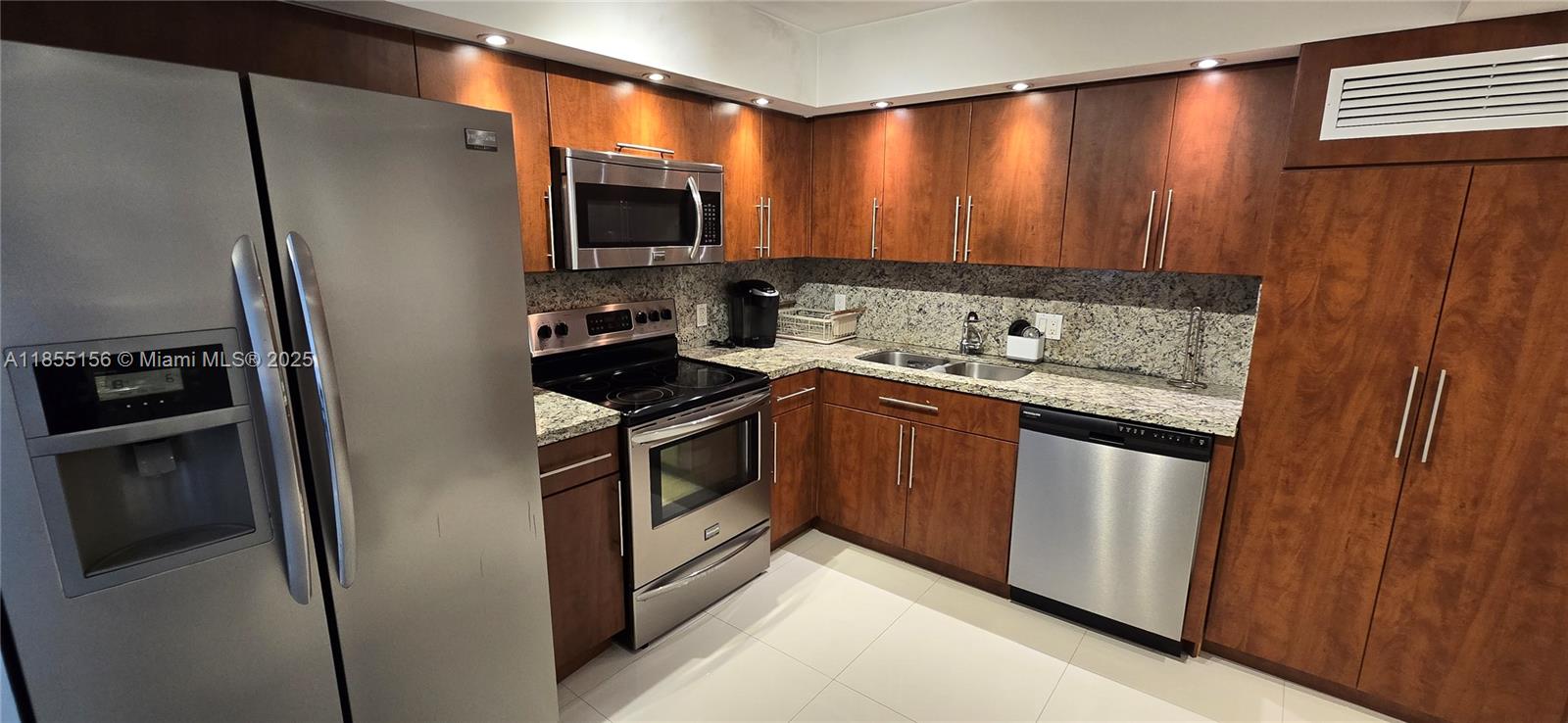 2801 Northeast 183rd Street, Unit 714W Aventura, FL 33160 - Photo 4 of 21 a kitchen with stainless steel appliances granite countertop a stove a refrigerator and a microwave