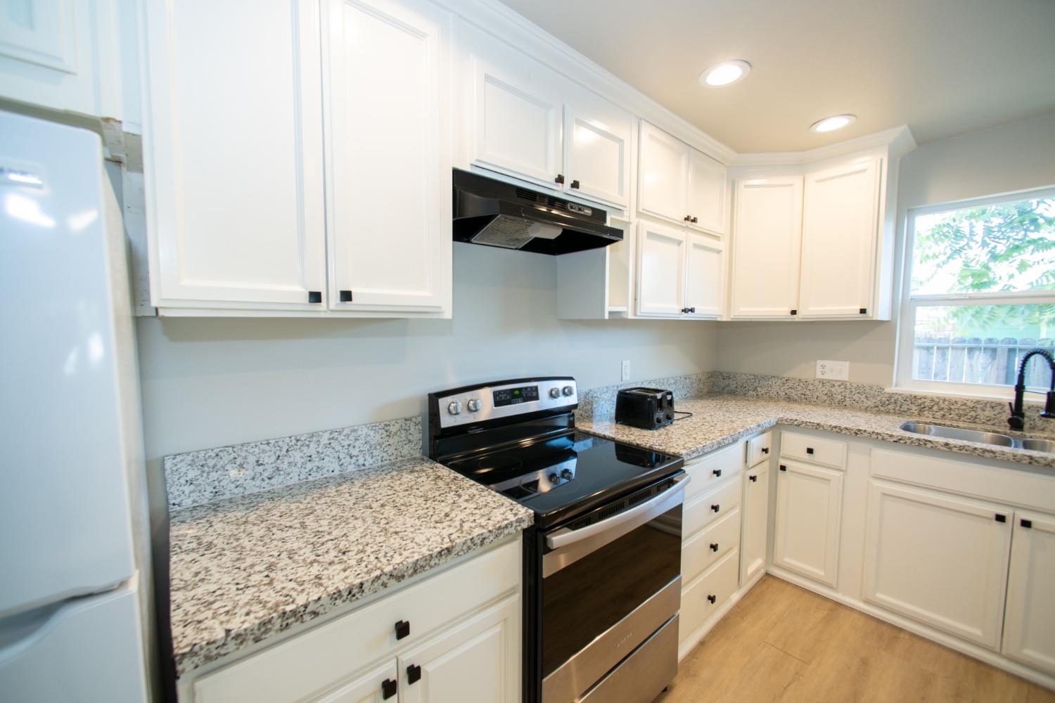 1136 East Griffith Way Fresno, CA 93704 - Photo 12 of 33 a kitchen with stainless steel appliances granite countertop white cabinets and a stove
