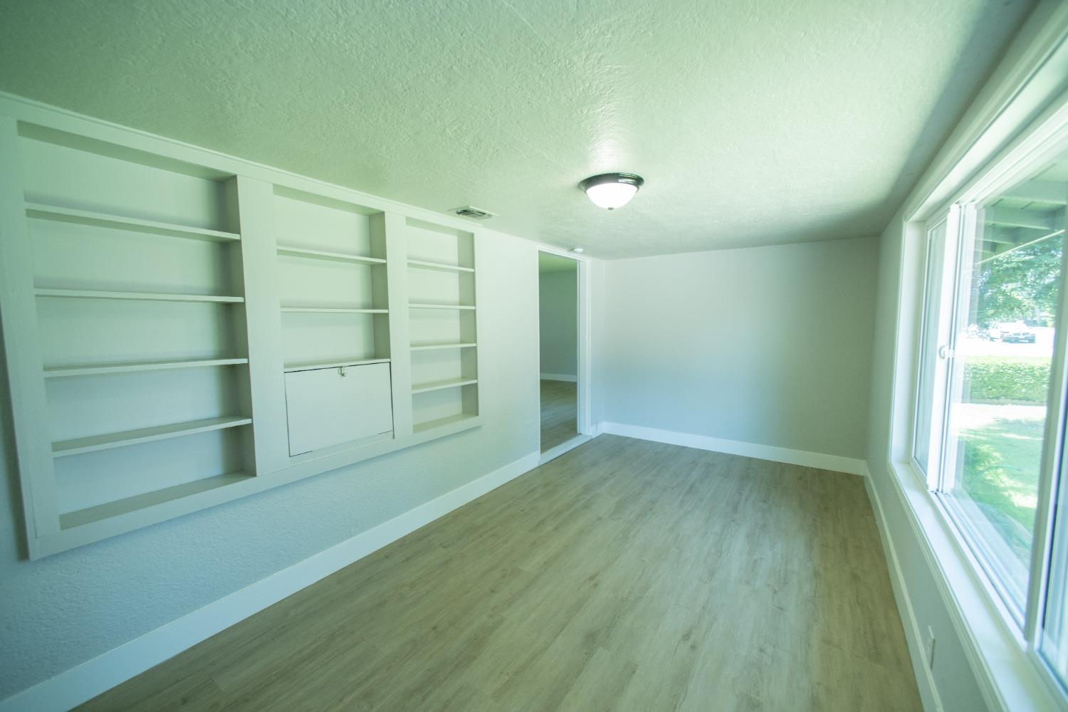 1136 East Griffith Way Fresno, CA 93704 - Photo 4 of 33 a view of an empty room with a window and wooden floor
