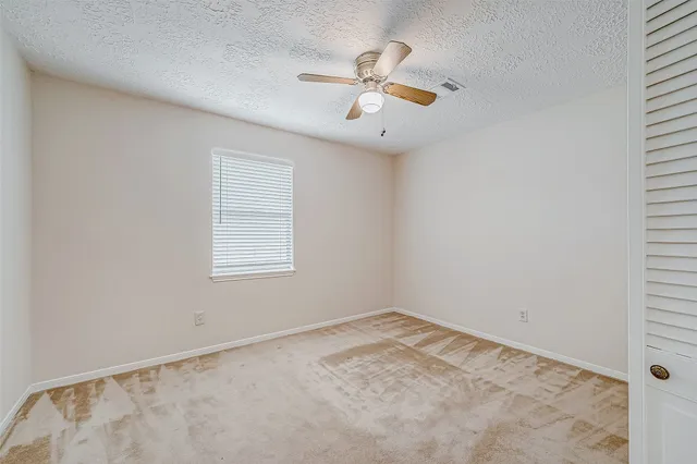 an empty room with a ceiling fan and a window