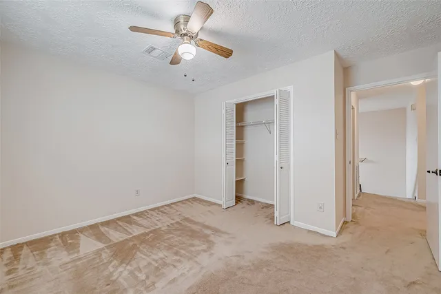 an empty room with closet and a chandelier fan