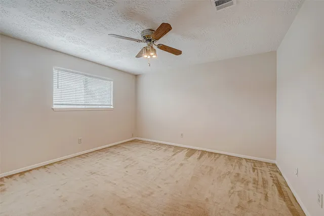 an empty room with windows and ceiling fan