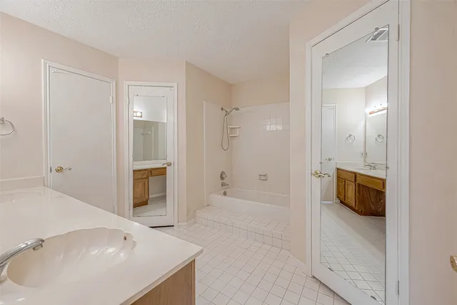 a spacious bathroom with a tub sink shower and mirror