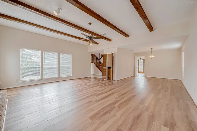 an empty room with wooden floor fireplace and windows