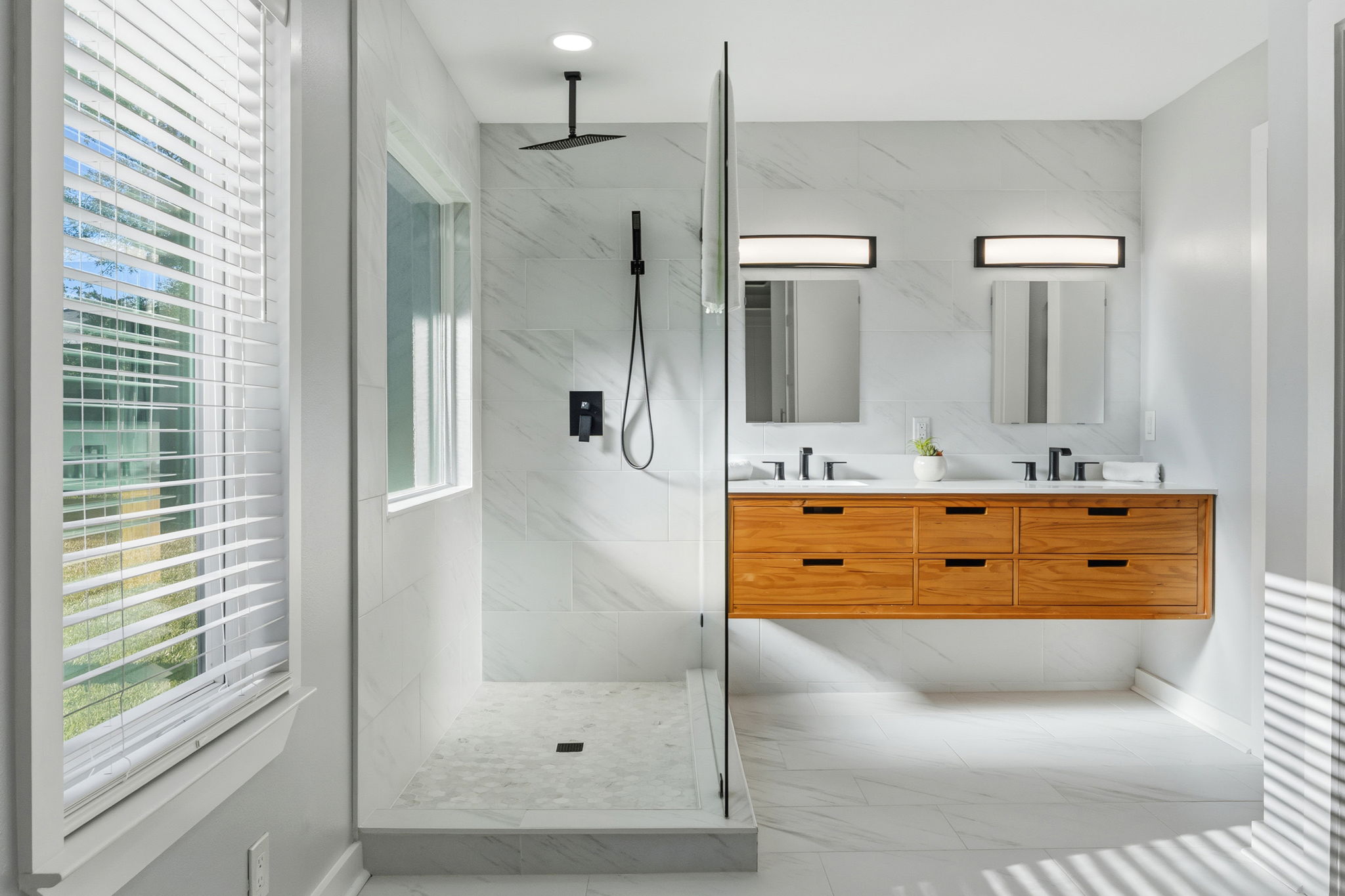 4802 Brighton Road Austin, TX 78745 - Photo 5 of 30 Stunning primary bathroom with floating dual-sink vanity with warm wood cabinetry, sleek matte black fixtures, and modern lighting creates a clean, contemporary look with generous storage.