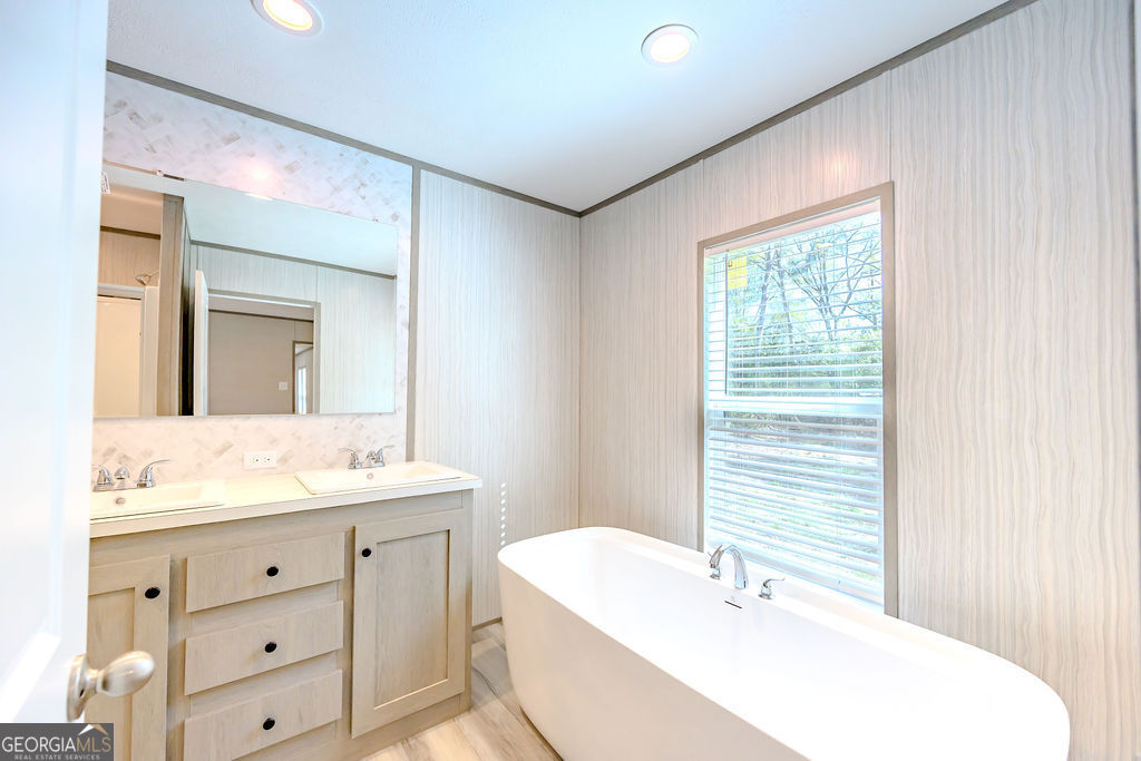 226 Mullis Street Dexter, GA 31019 - Photo 16 of 37 a bathroom with a bathtub a sink a vanity and a window