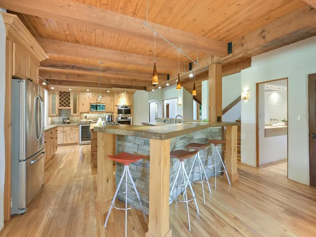 a kitchen with stainless steel appliances kitchen island granite countertop a refrigerator a stove and a wooden floors