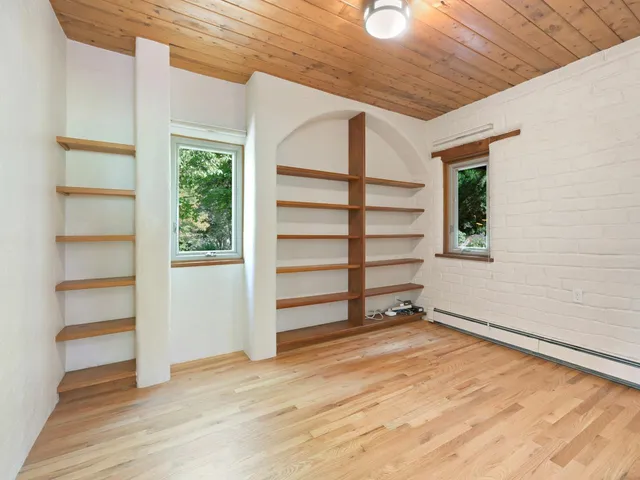 a view of an empty room with a window and wooden floor